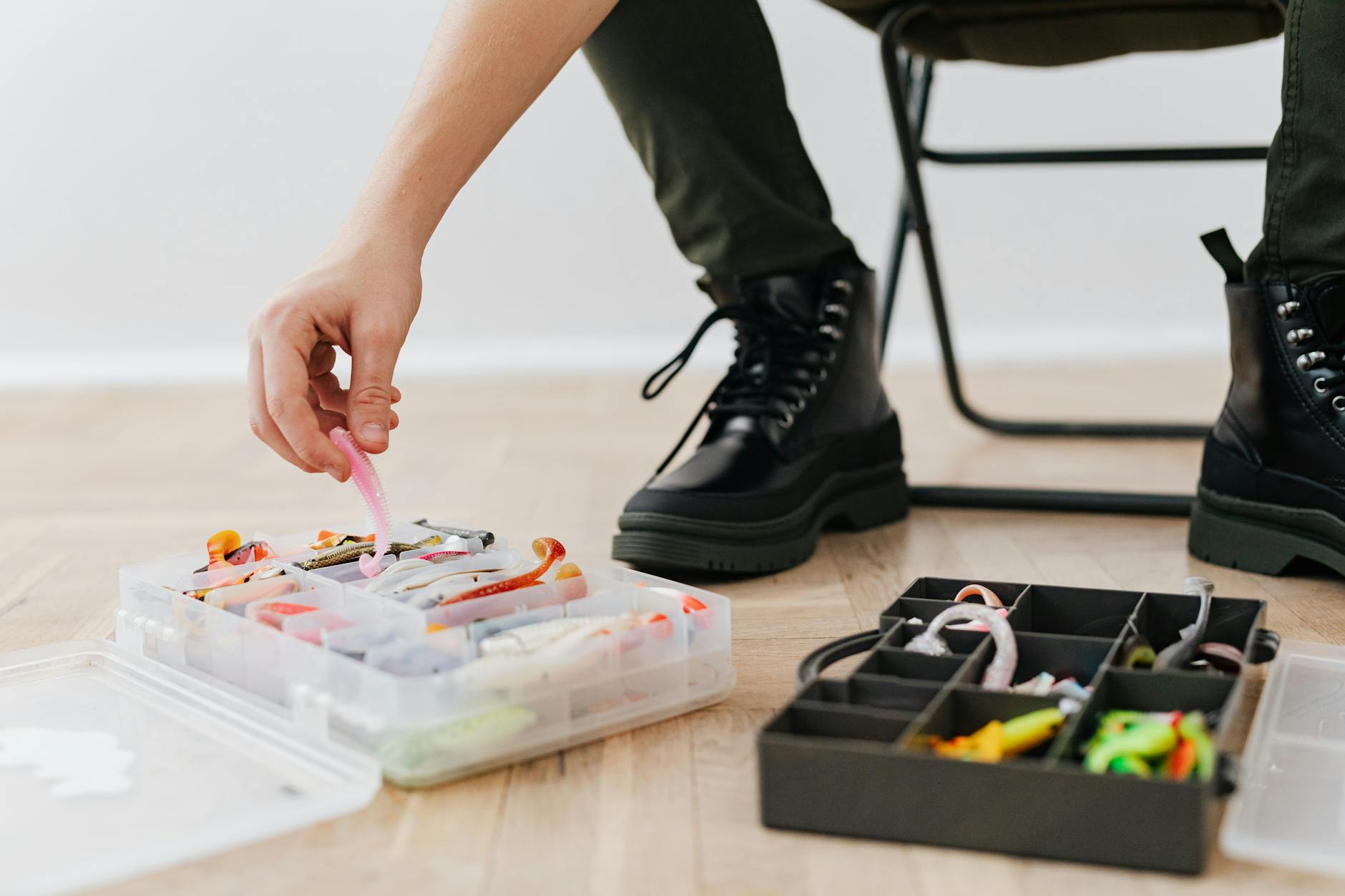 Jak przechowywać robaki i pinki, żeby były żywe przez całą zasiadkę Wędkarz segreguje przynęty w plastikowych pudełkach w pomieszczeniu